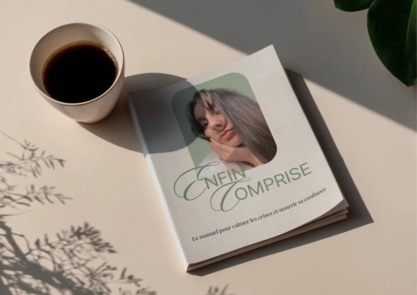 Le guide Enfin Comprise posé sur une table, à côté d’une tasse de café, dans une lumière de fin de journée